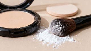 Compact powder and brush with scattered talcum powder illustrating talc in makeup safety concerns